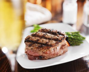 grilled steak filet with white wine and asparagus on wooden table with white wine